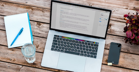 Open Mac on a table with Essay visible