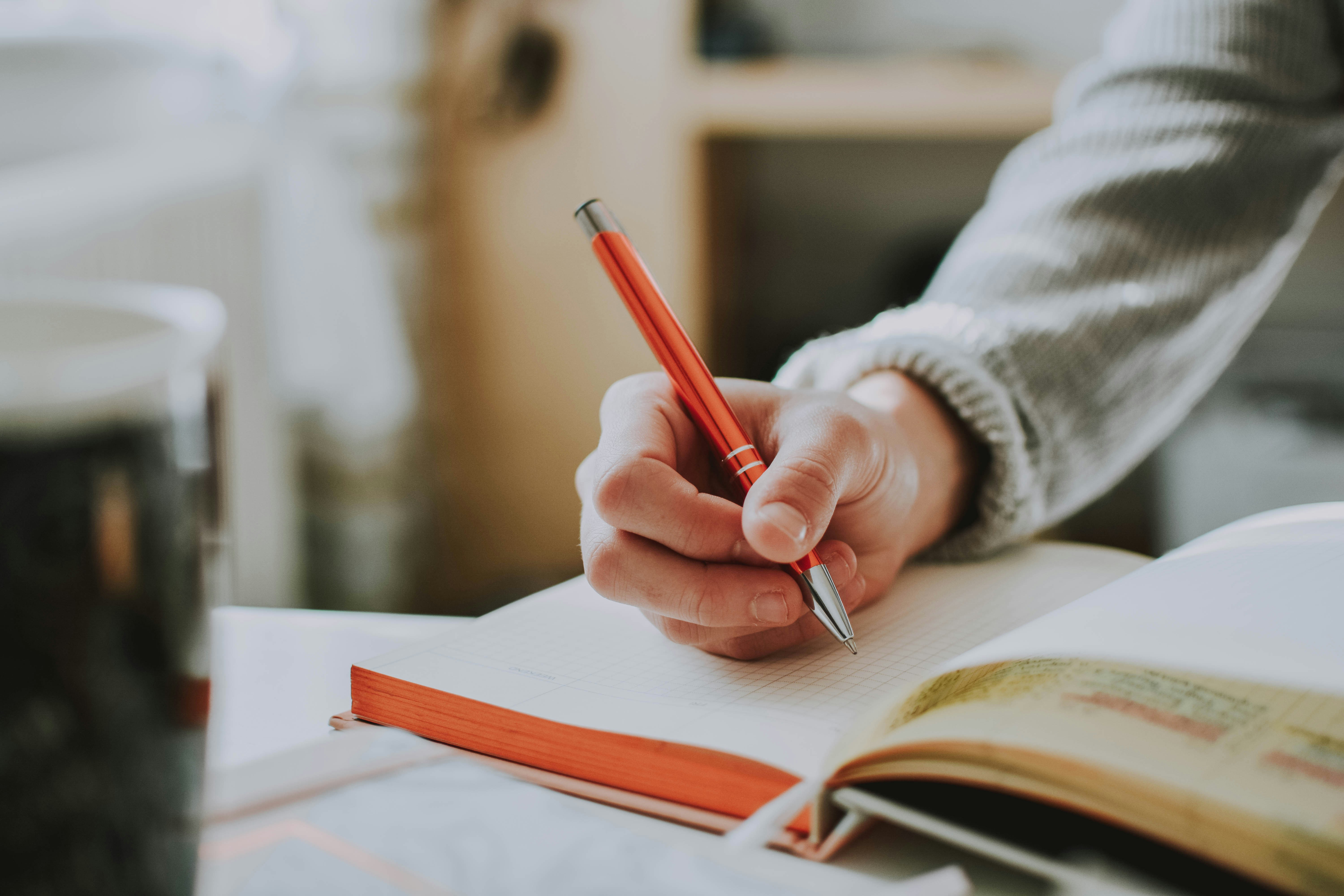 Person writing on a notepad with pen