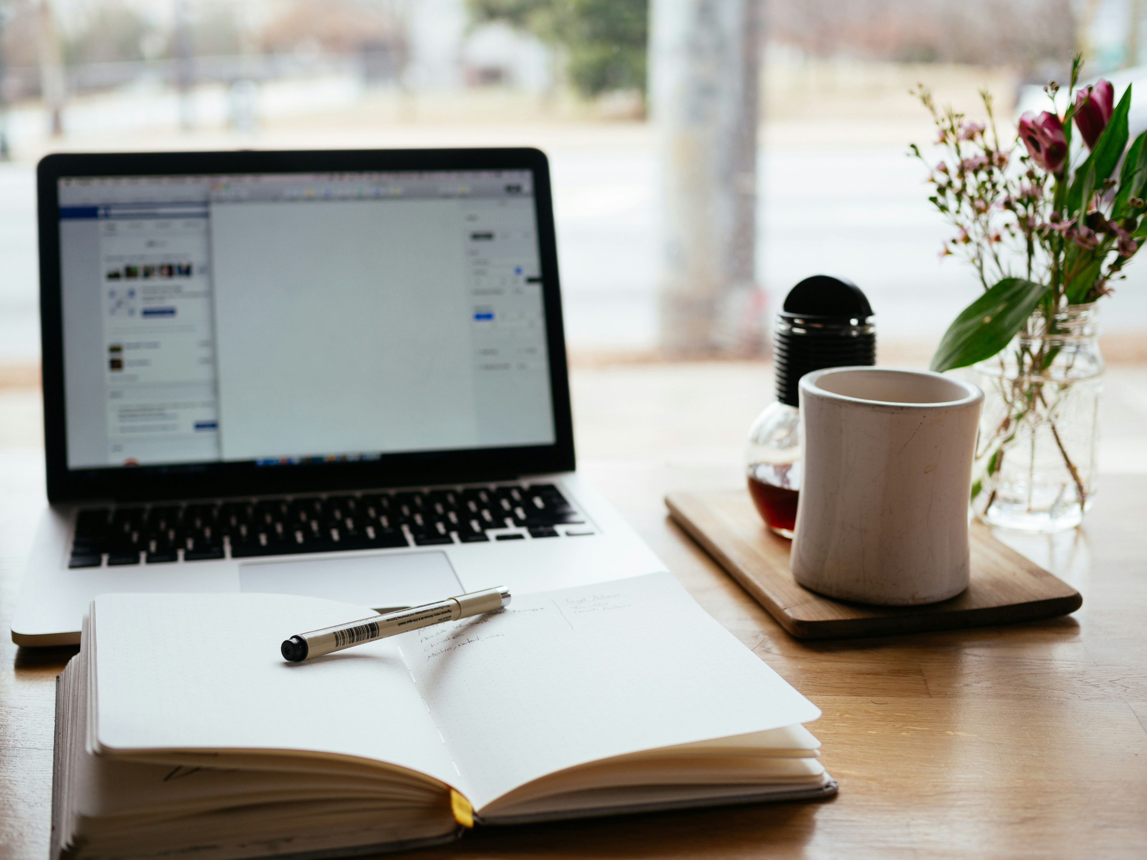 A laptop, Coffee and a book resting on table