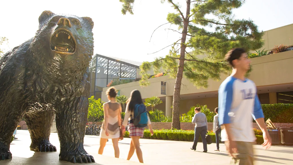 A group of people walking around a statue of a bear